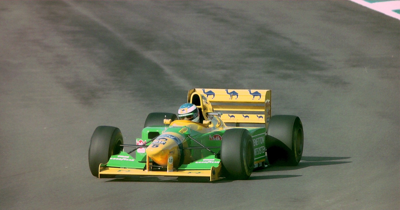 Green and yellow Benetton Formula One car number 5 driven by Michael Schumacher on a dry track