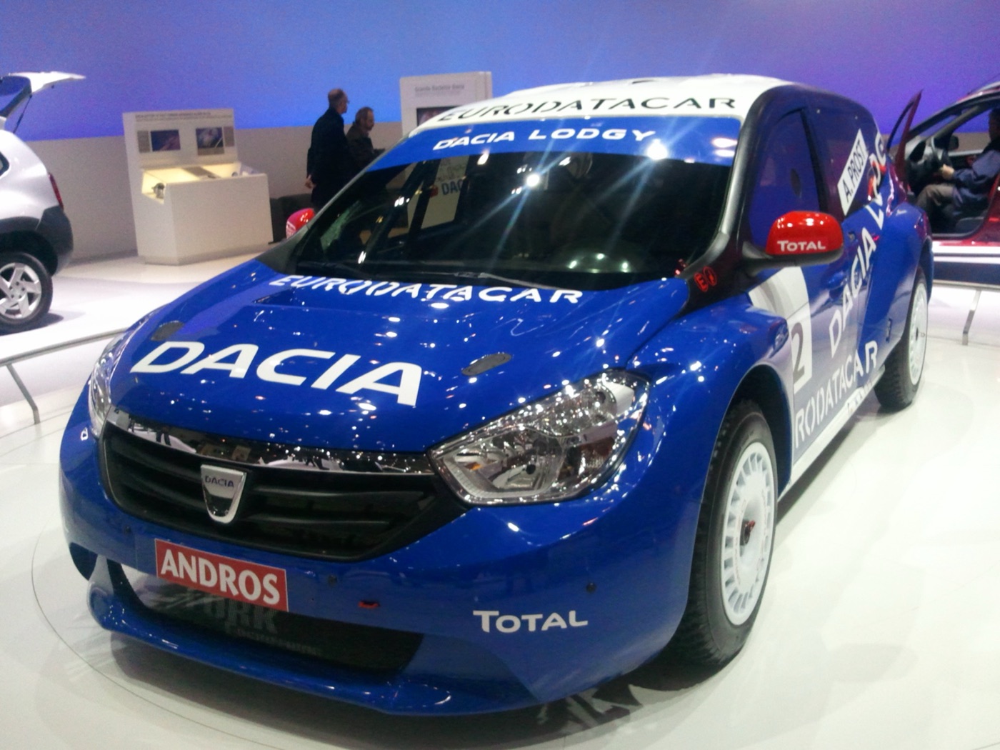 Blue and white Dacia Lodgy Glace ice-racing car with Andros, Total and A. Prost lettering on display on a motor show stand