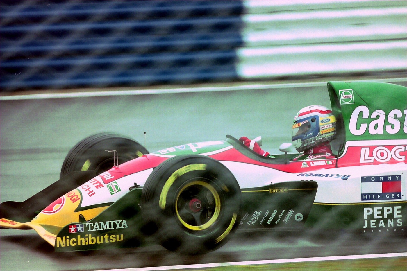 Green, white and red Lotus 107B Formula One car on a wet track, Zanardi in a blue, red and yellow helmet