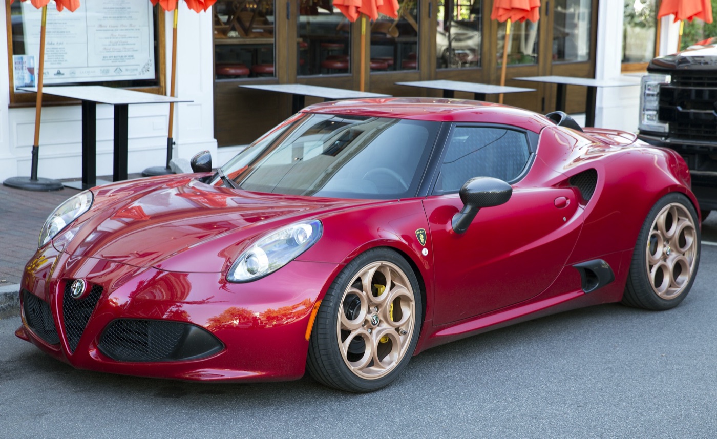 Red Alfa Romeo 4C coupé with bronze five-hole wheels and black carbon trim parked on a street