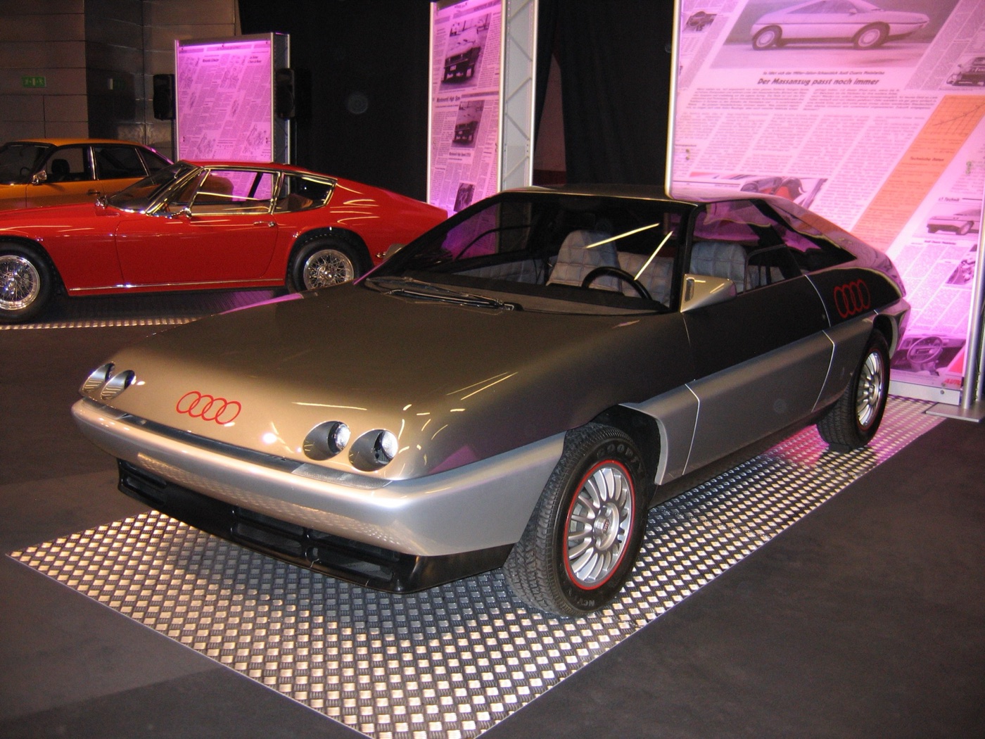 Silver and dark grey Audi Quartz concept coupé with two pairs of small round headlamps, on a show stand