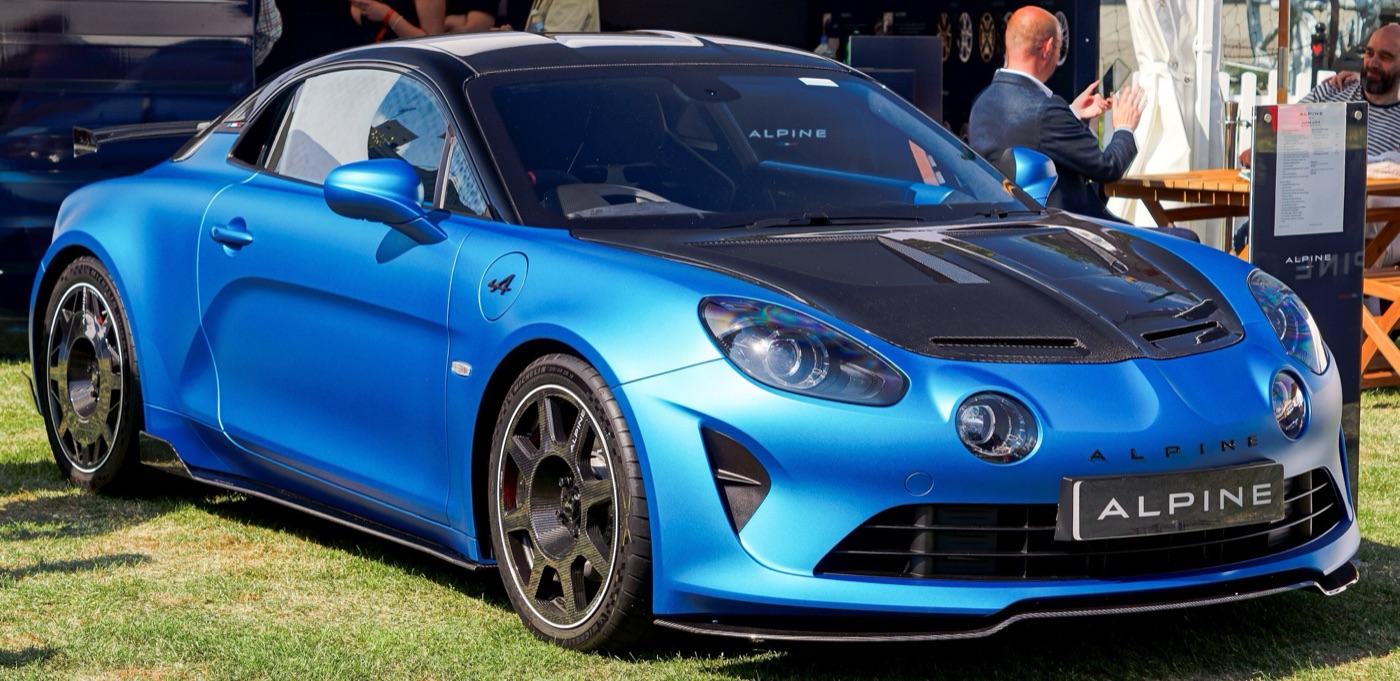 Blue Alpine A110 R with a black carbon-fibre bonnet and carbon wheels on grass