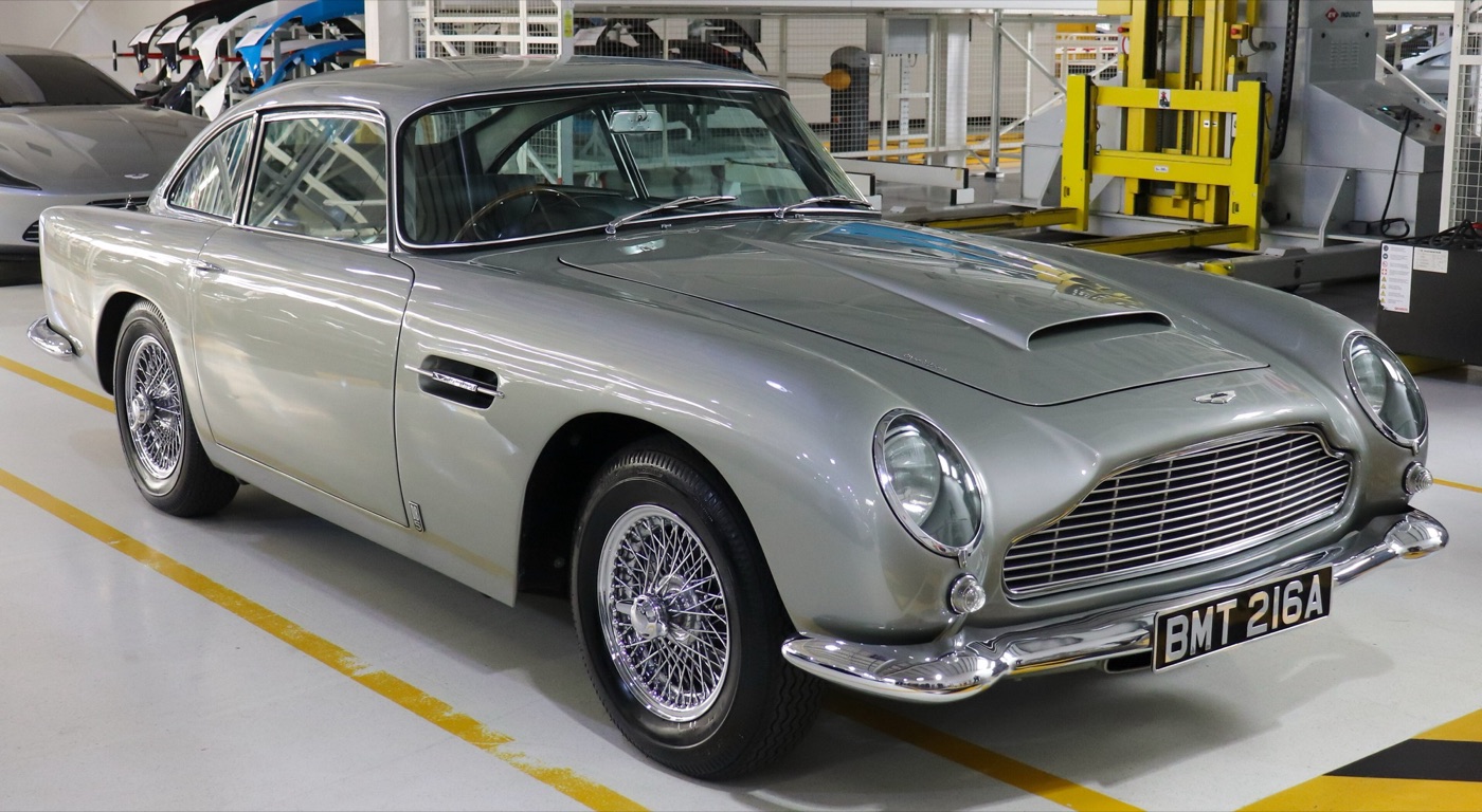 Silver Aston Martin DB5 saloon with BMT 216A number plates, wire wheels and covered headlamps, indoors at the Aston Martin factory