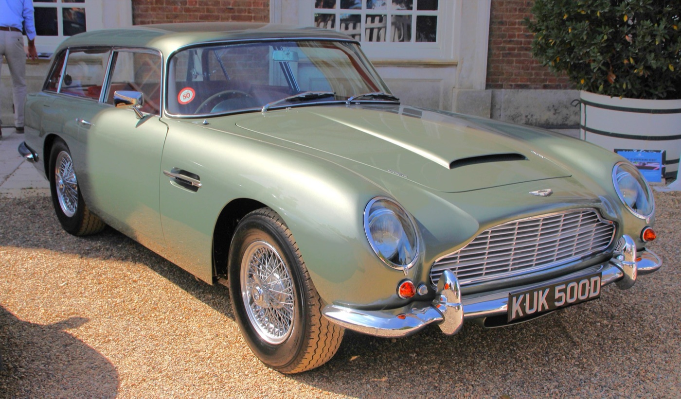 Pale green DB5 shooting brake with the extended estate roof, parked on gravel in front of a brick building