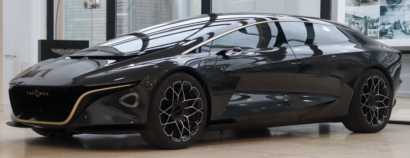 Black Lagonda Vision Concept, a long low electric saloon with gold trim, in a showroom