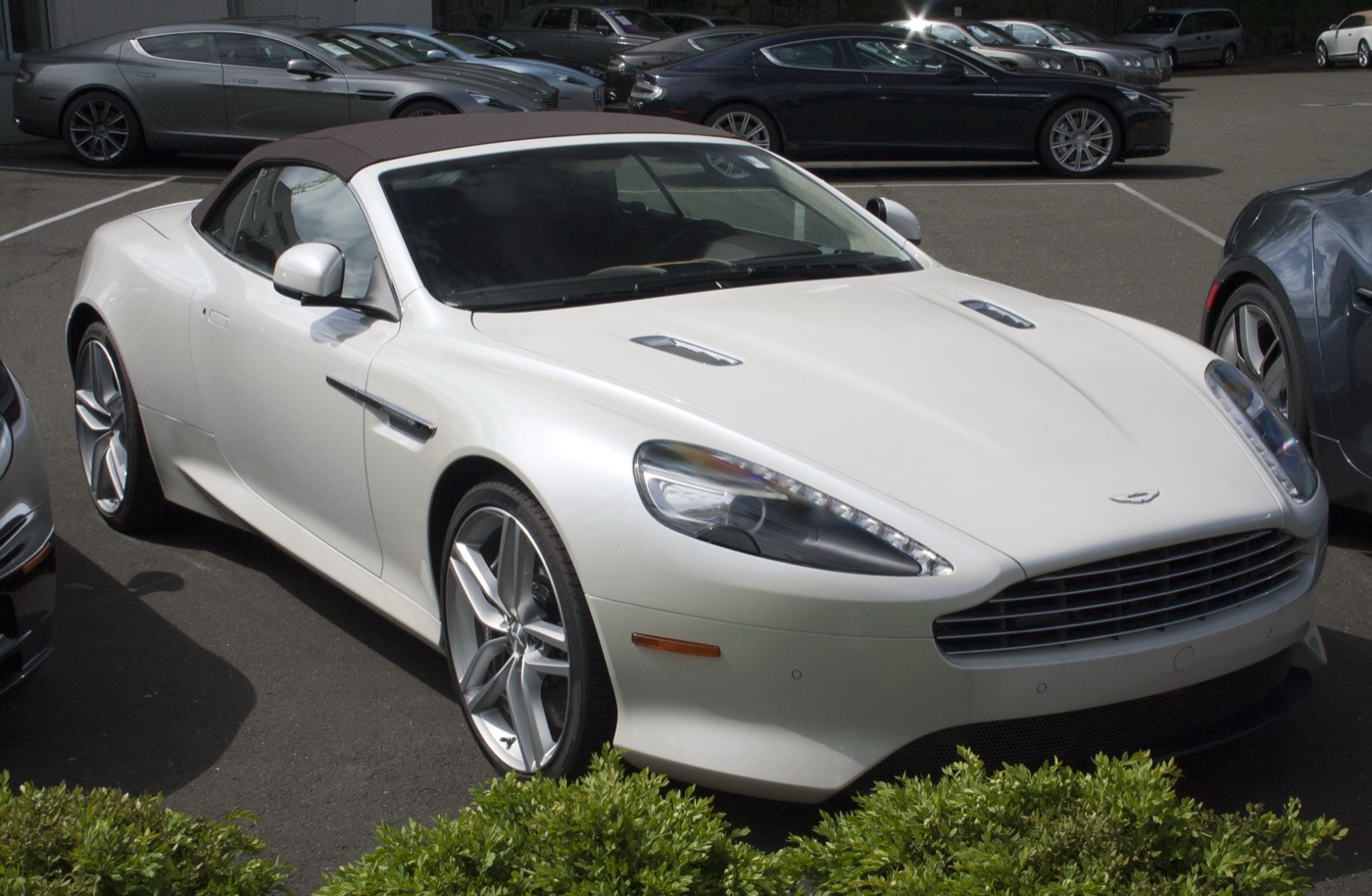 White 2012 Aston Martin Virage Volante with its brown fabric roof raised, parked at a dealership