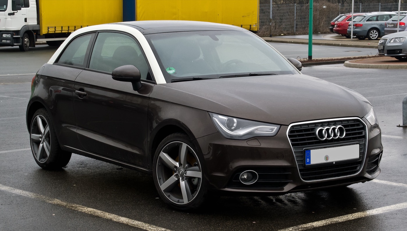 Dark brown Audi A1 three-door with a white contrast roof arch parked in a wet car park