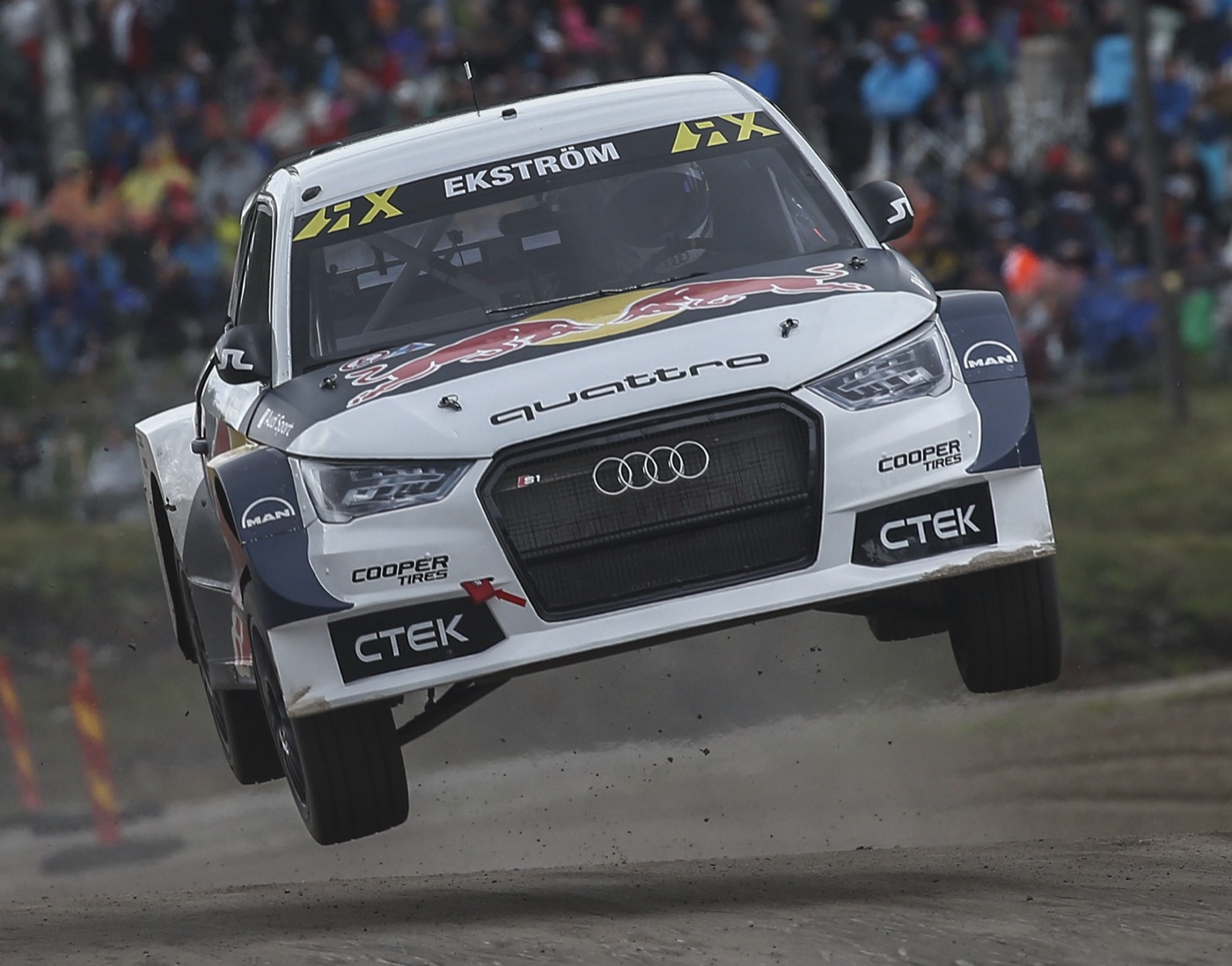 White Audi S1 EKS RX quattro rallycross car airborne over a jump in front of a crowd