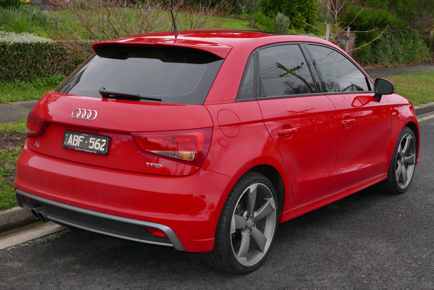 Red Audi A1 Sportback five-door seen from the rear three-quarter on a suburban street