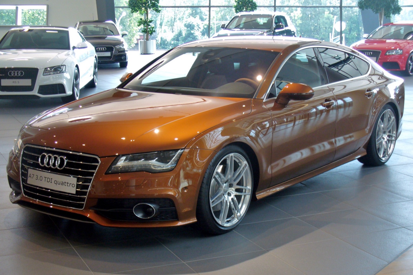 Ipanema brown pre-facelift Audi A7 Sportback 3.0 TDI quattro S line in a dealer showroom, front three-quarter view