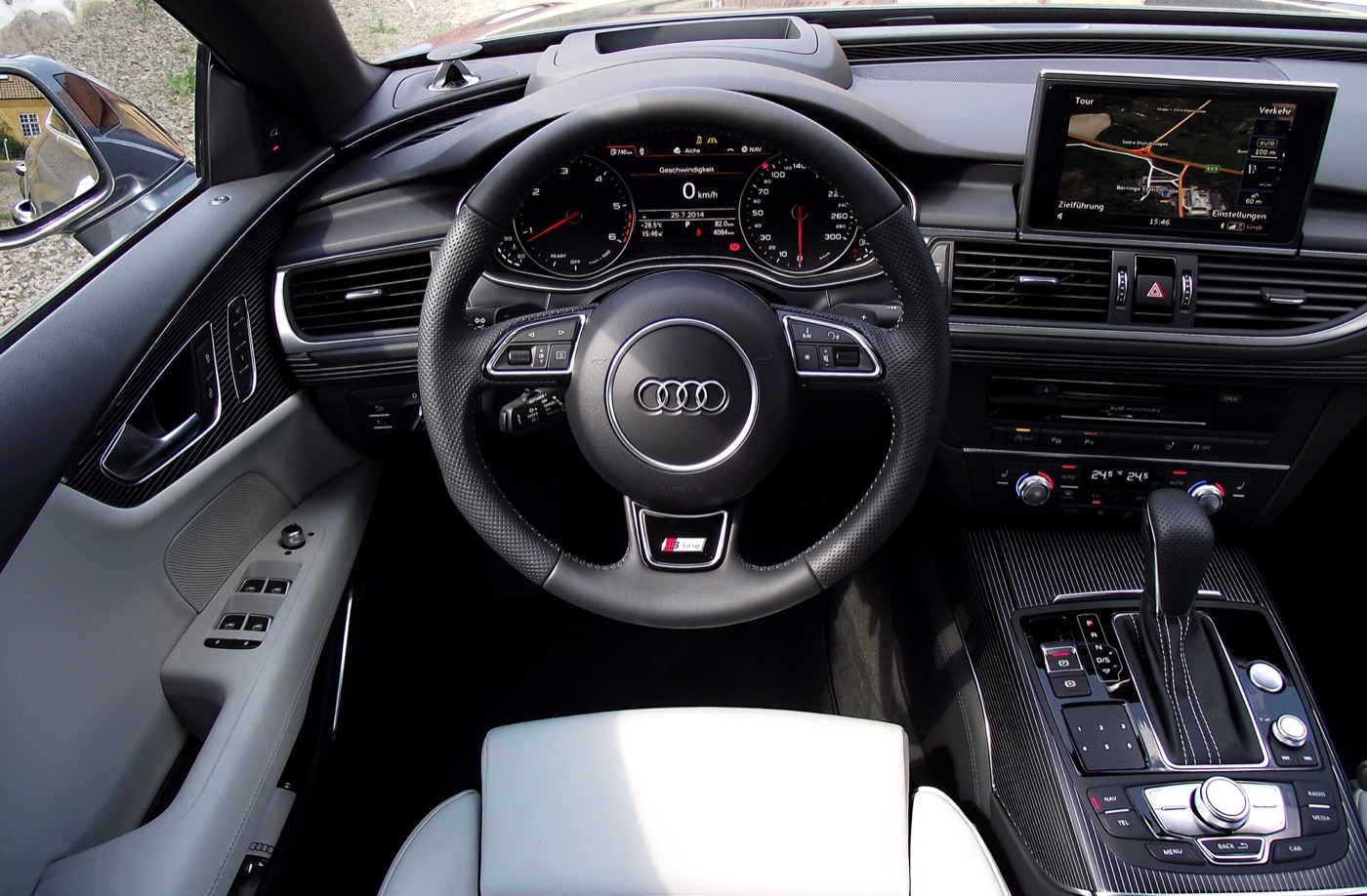 Dashboard of a facelifted Audi A7 Sportback with the MMI screen raised, S line steering wheel and light grey leather seats