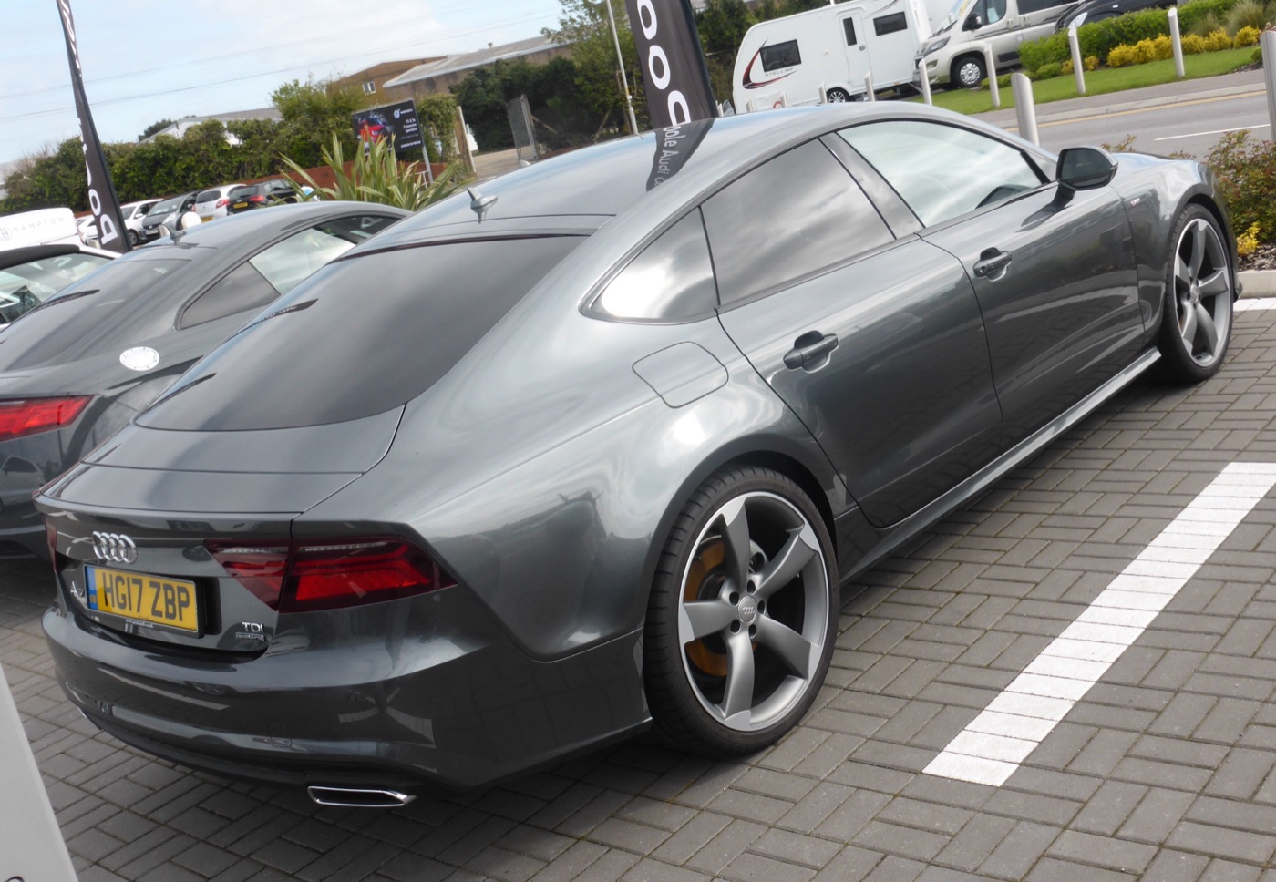Grey facelifted Audi A7 TDI quattro Black Edition with black rotor-design wheels and dark trim, rear three-quarter view