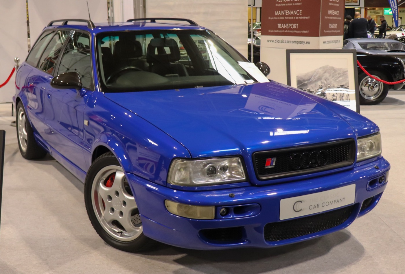 Nogaro blue Audi RS2 on a dealer’s stand indoors, with a Classic Car Company plate in place of the front number plate