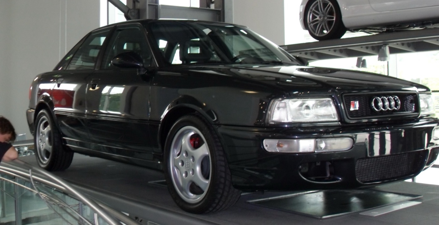 Black Audi RS2 saloon with red brake calipers and Cup wheels on a display plinth indoors
