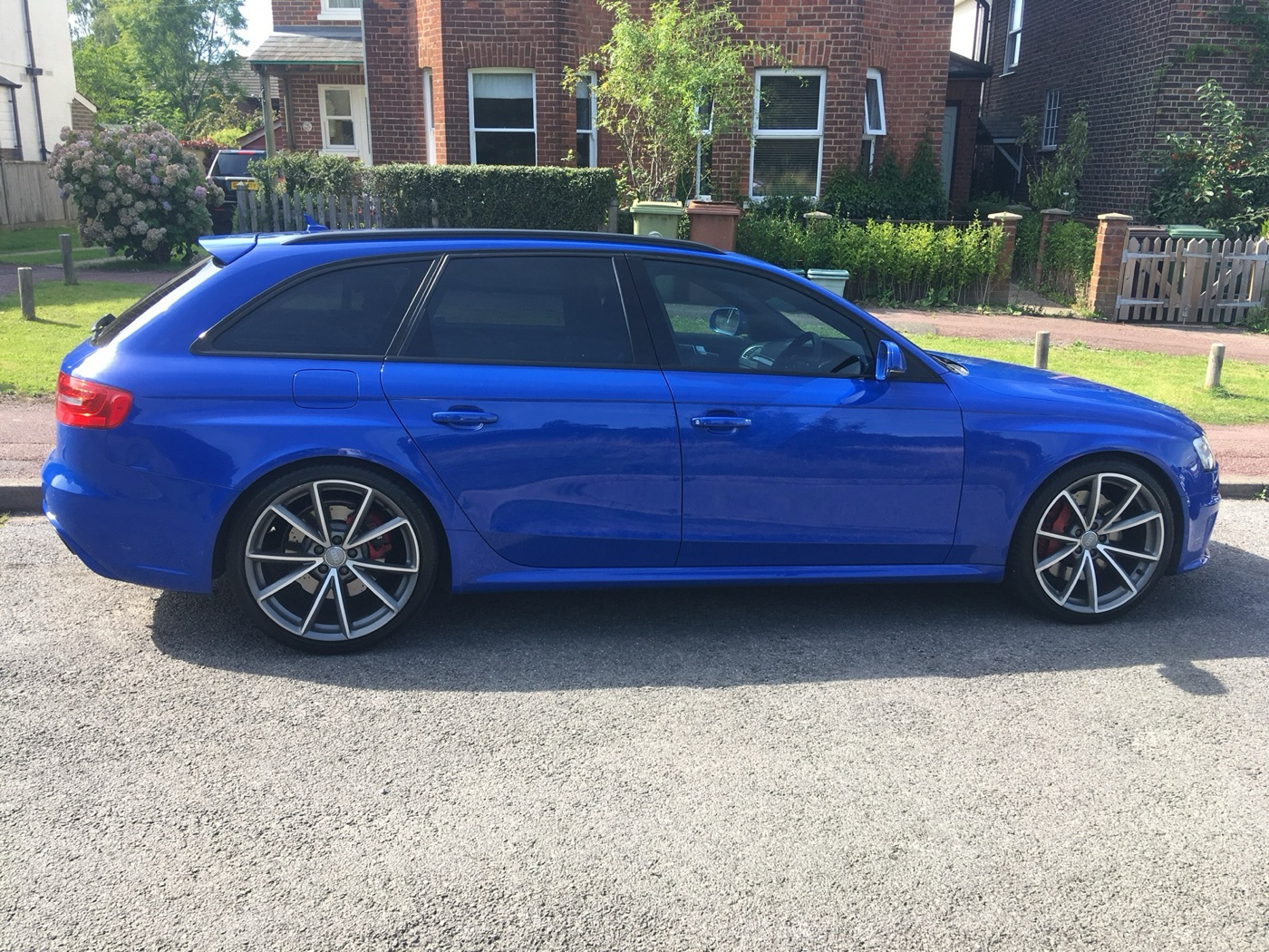 Side view of a Nogaro blue Audi RS4 Avant B8 with ten-spoke alloy wheels parked on a residential street