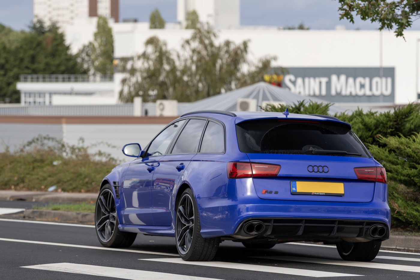 Nogaro blue Audi RS6 Avant performance Nogaro Edition seen from the rear on Dutch plates, with black wheels and oval tailpipes