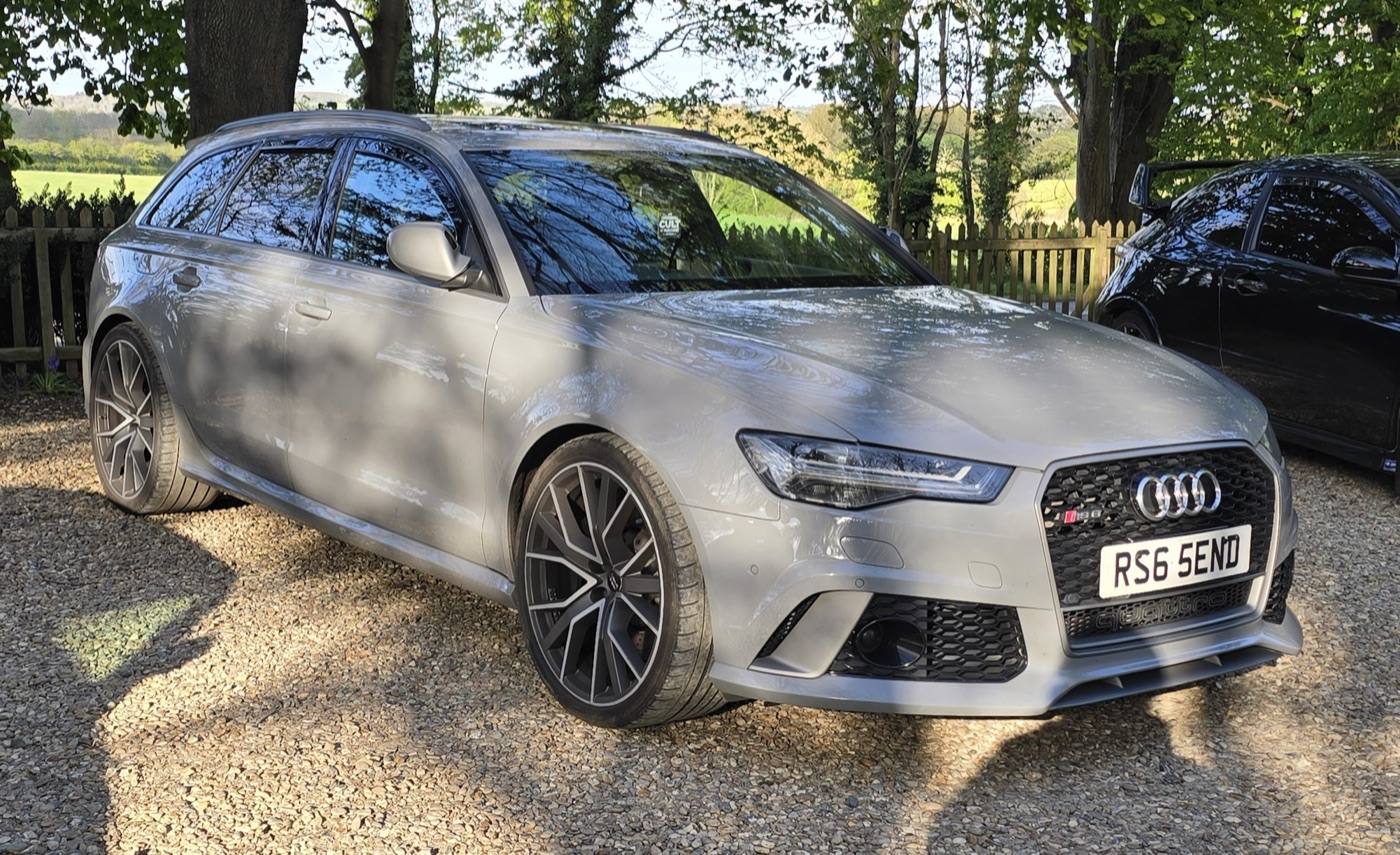 Grey facelifted Audi RS6 Avant performance C7 with dark multi-spoke wheels, parked on gravel on UK plates
