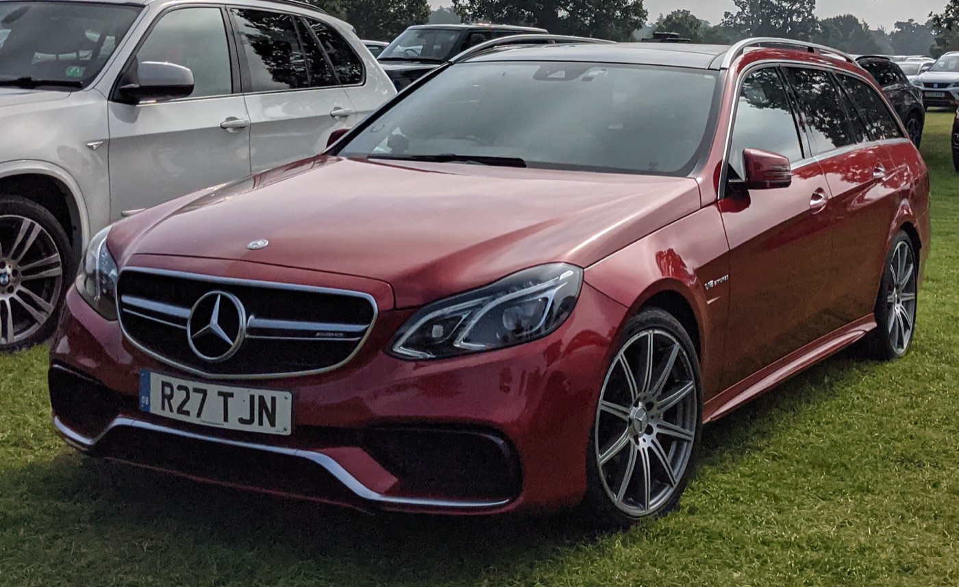 Red Mercedes-Benz E63 AMG estate of the S212 generation, a rival to the RS6 C7, parked on grass on UK plates