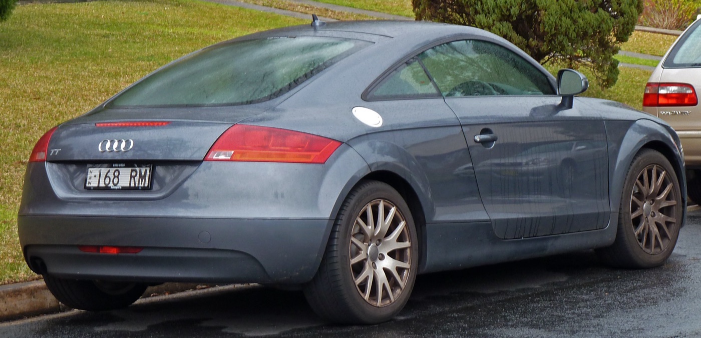 Grey Audi TT Mk2 2.0 TFSI coupe seen from the rear quarter on a wet suburban street