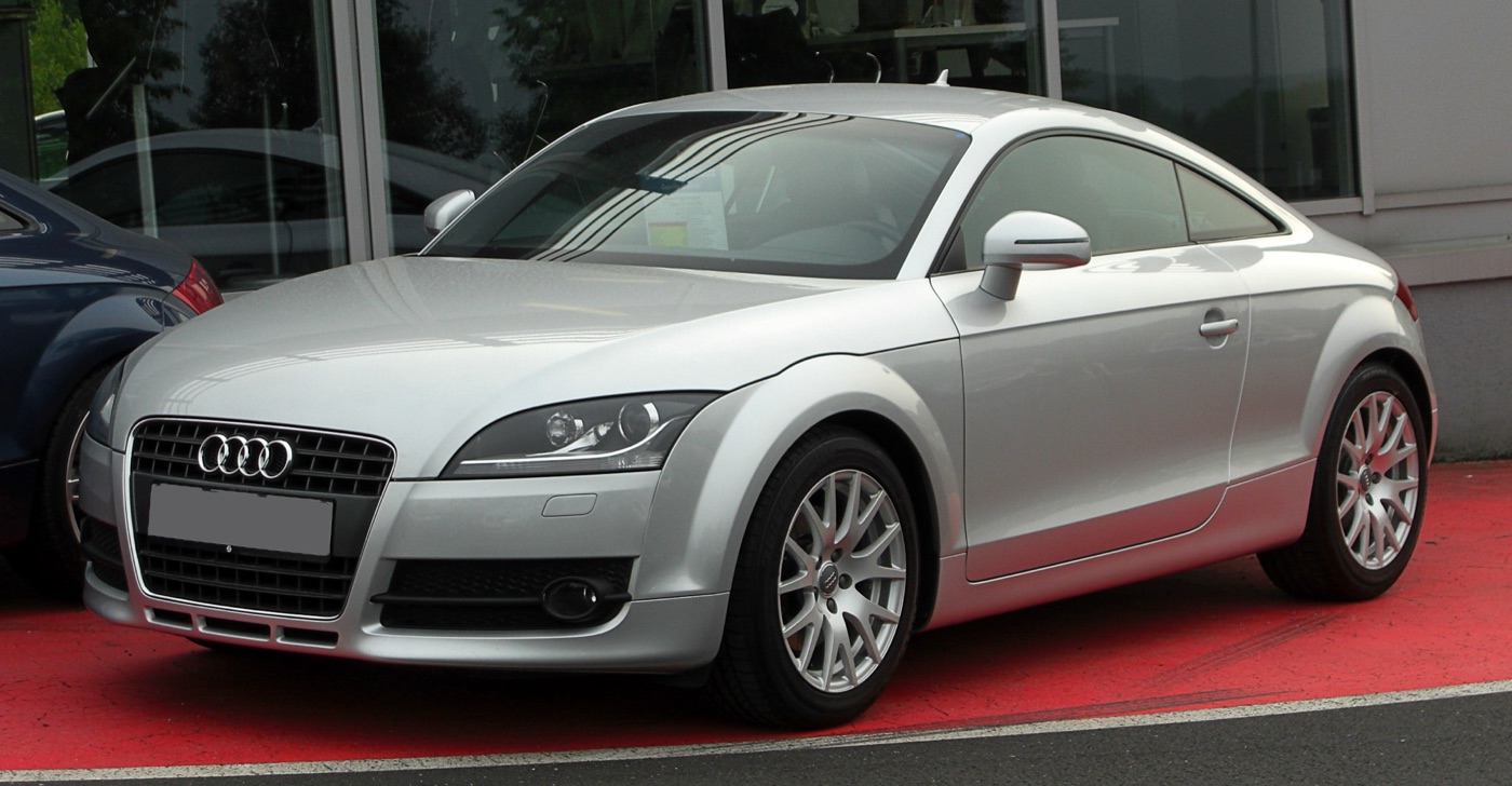 Silver pre-facelift Audi TT Mk2 coupe with a single-frame grille parked on a red forecourt