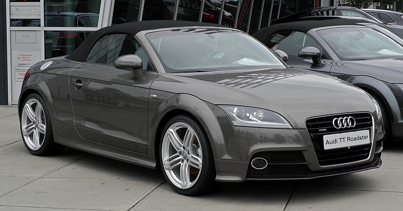 Grey facelifted Audi TT Roadster S line with its black fabric hood raised outside a dealership