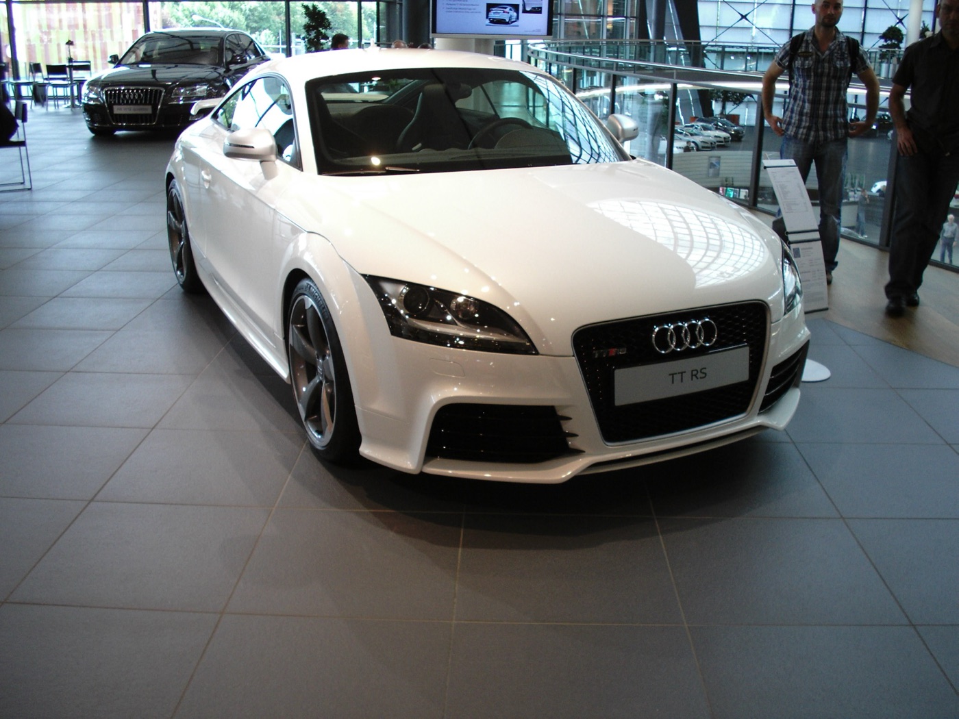 White Audi TT RS coupe with dark five-spoke wheels on display inside the Audi Forum