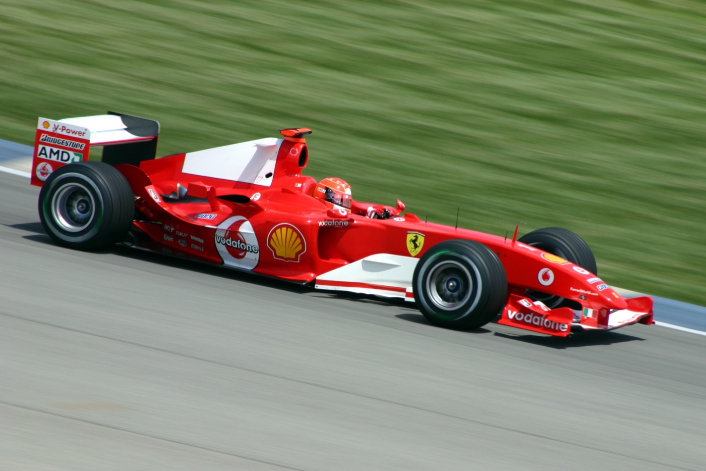 Michael Schumacher’s red Ferrari F2004 at speed past a blurred grass verge