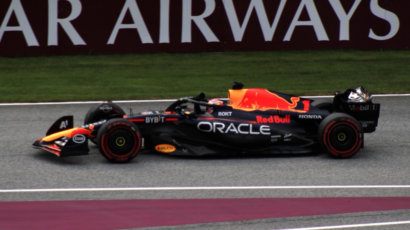 Max Verstappen’s dark blue Red Bull RB19 with Oracle and Red Bull logos on track beside an advertising hoarding