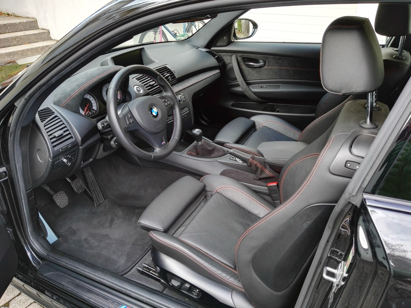 Front seats and dashboard of a BMW 1M with black leather, grey Alcantara and orange stitching