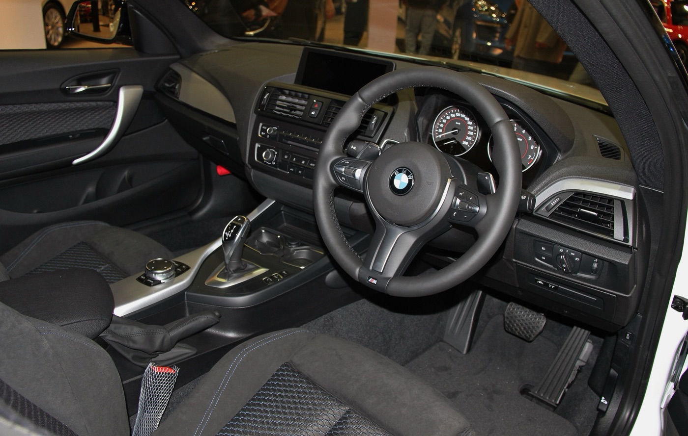 Dashboard of a right-hand-drive BMW 220i Coupé M Sport with automatic gear selector, M steering wheel and iDrive screen on top of the dash