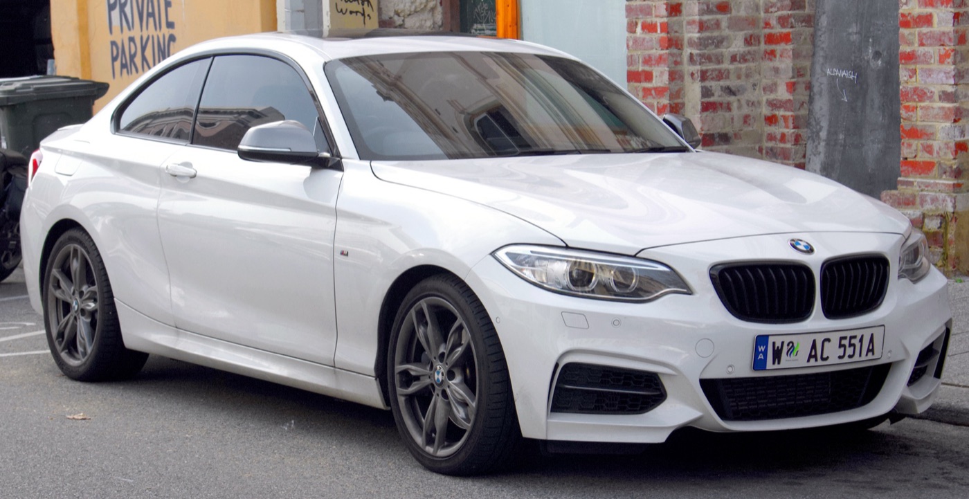 White BMW M235i coupé with grey mirror caps and dark grey alloy wheels parked in a street