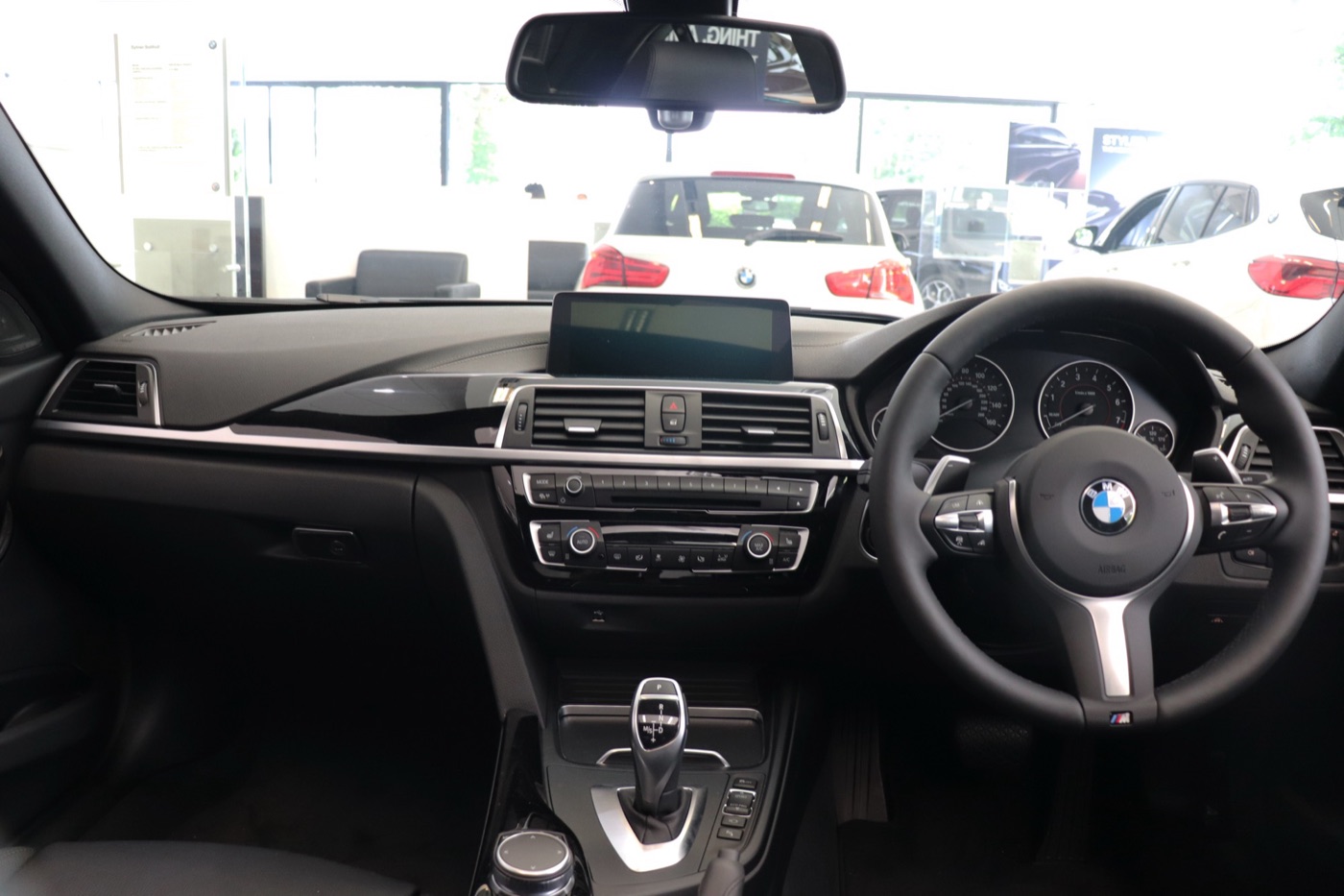 Dashboard of a right-hand-drive BMW 340i M Sport with the iDrive screen on top, M steering wheel and automatic gear selector