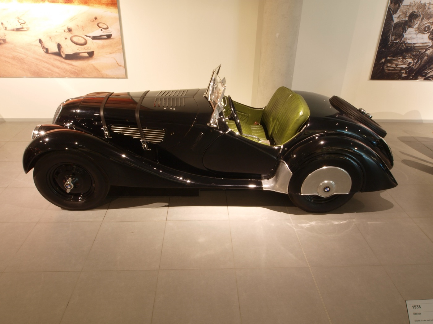 Black BMW 328 roadster in profile with green leather seats, two bonnet straps, a louvred bonnet and the spare wheel in the tail