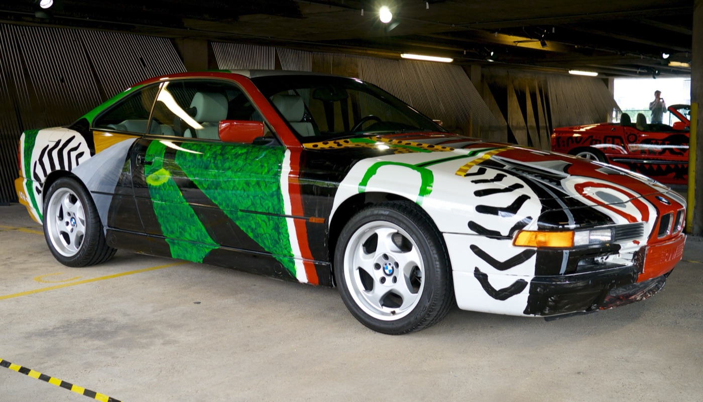 David Hockney’s BMW 850 CSi Art Car painted with green foliage, black stripes and a door showing the outline of a driver, in a car park