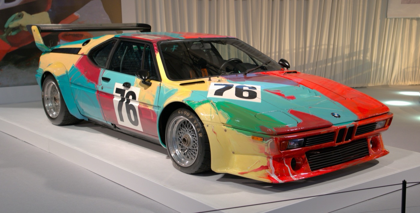 Andy Warhol’s BMW M1 Art Car, race number 76, with thick brushstrokes of red, green, blue and yellow, on a white stand