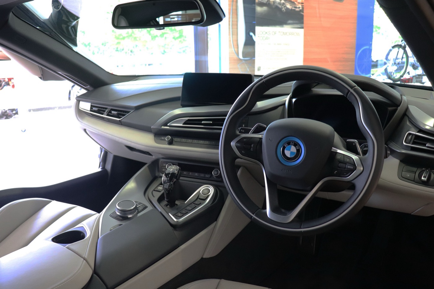 Right-hand-drive BMW i8 cabin with grey leather seats, the BMW i steering wheel, the gear selector and the iDrive controller