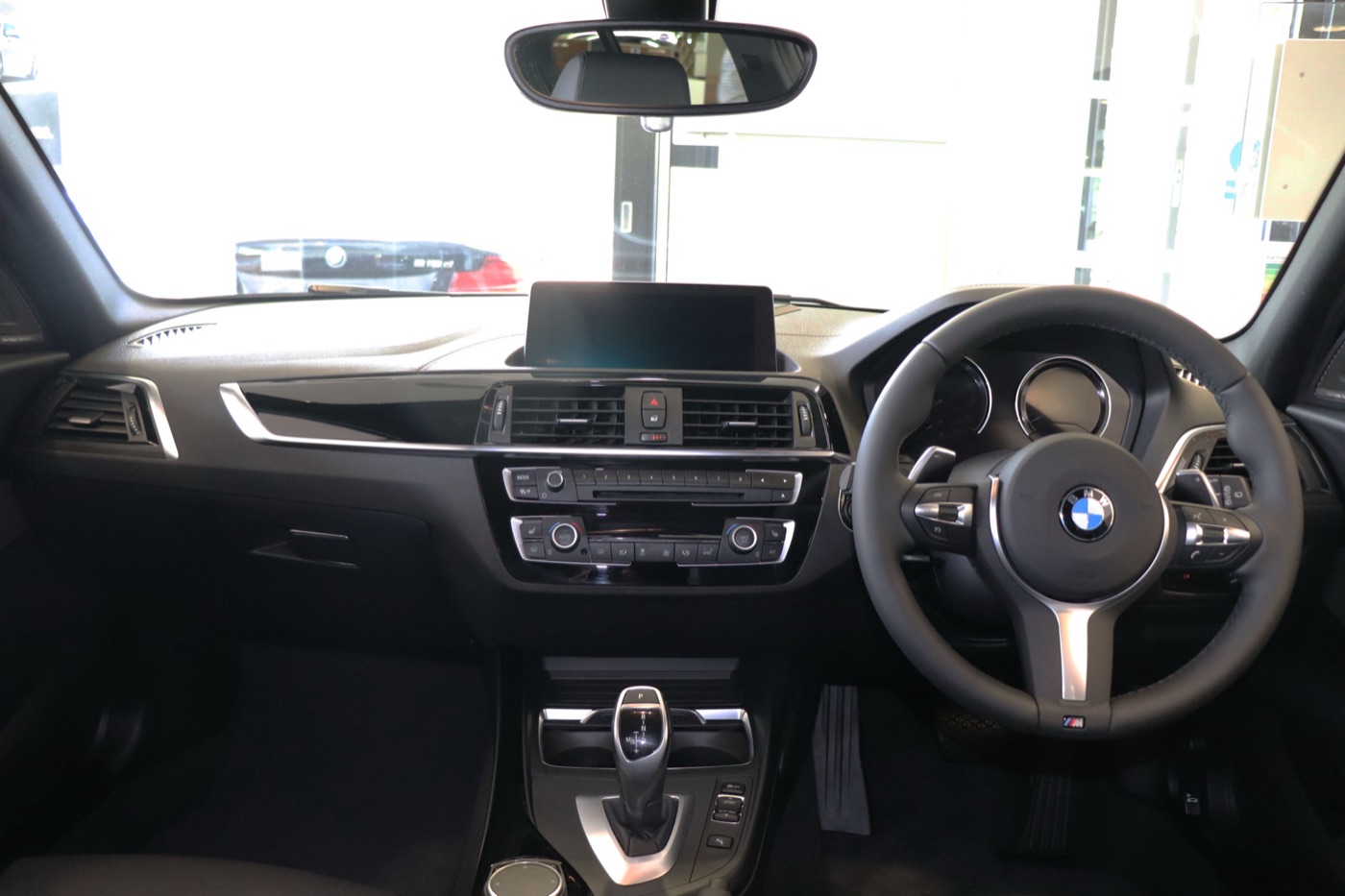 Dashboard of a right-hand-drive BMW M140i Shadow Edition with M steering wheel, iDrive screen and automatic gear selector