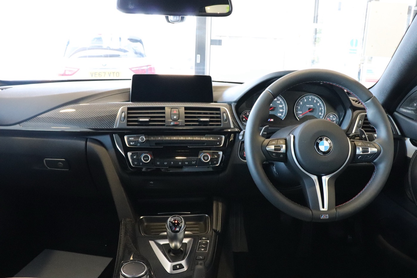 Right-hand-drive BMW M4 Competition dashboard with M steering wheel, twin dials, carbon trim and DCT gear selector