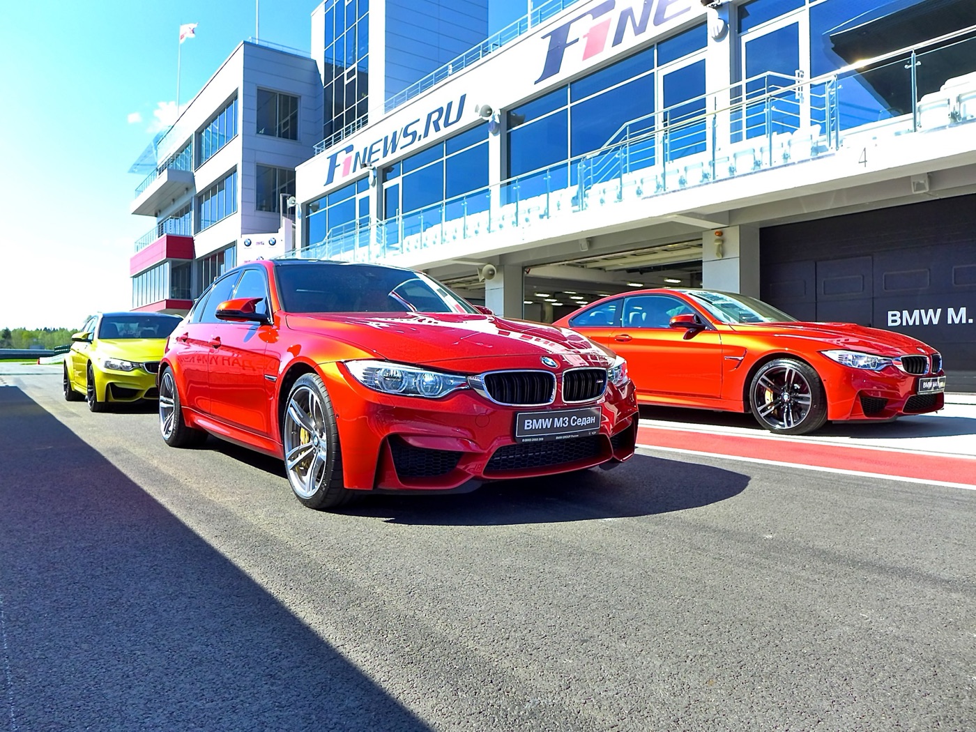 Red F80 M3 saloon in front of an orange F82 M4 and a yellow M4 in the pit lane at Moscow Raceway