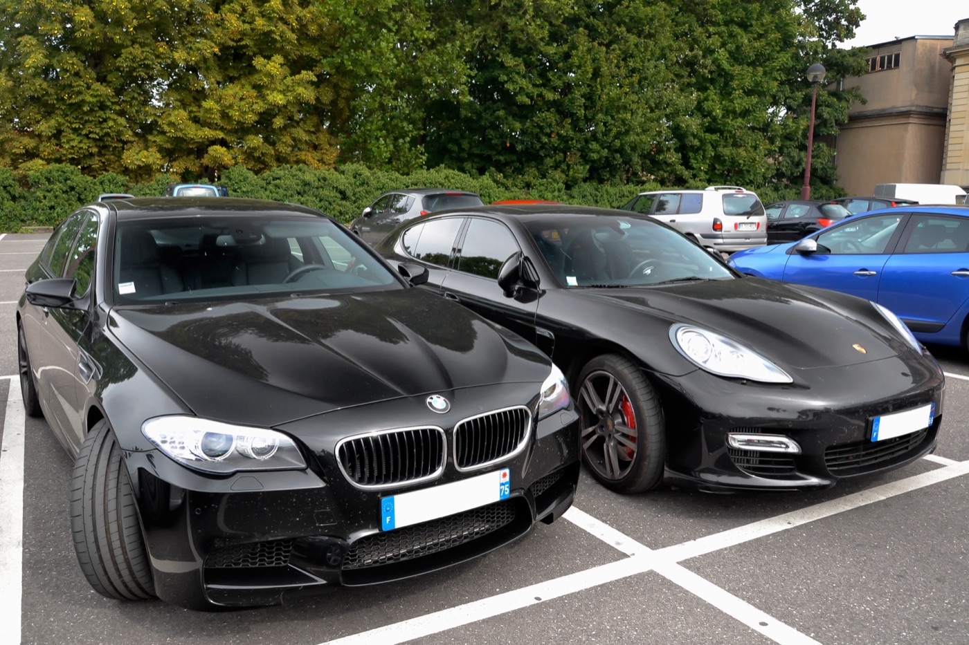 Black BMW M5 F10 parked beside a black Porsche Panamera Turbo in a car park