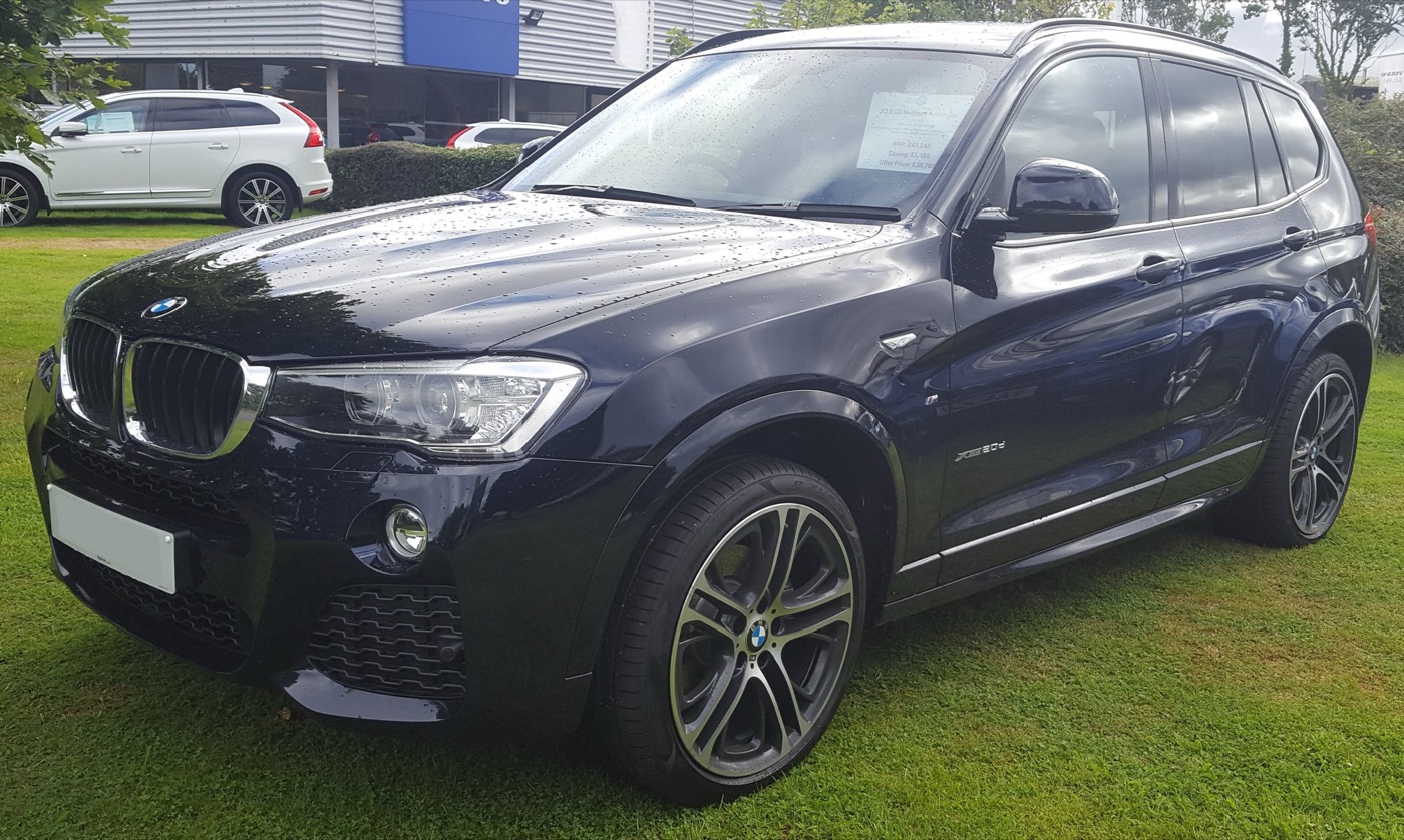 Dark blue facelifted BMW X3 xDrive20d M Sport with large two-tone alloy wheels parked on grass at a dealer