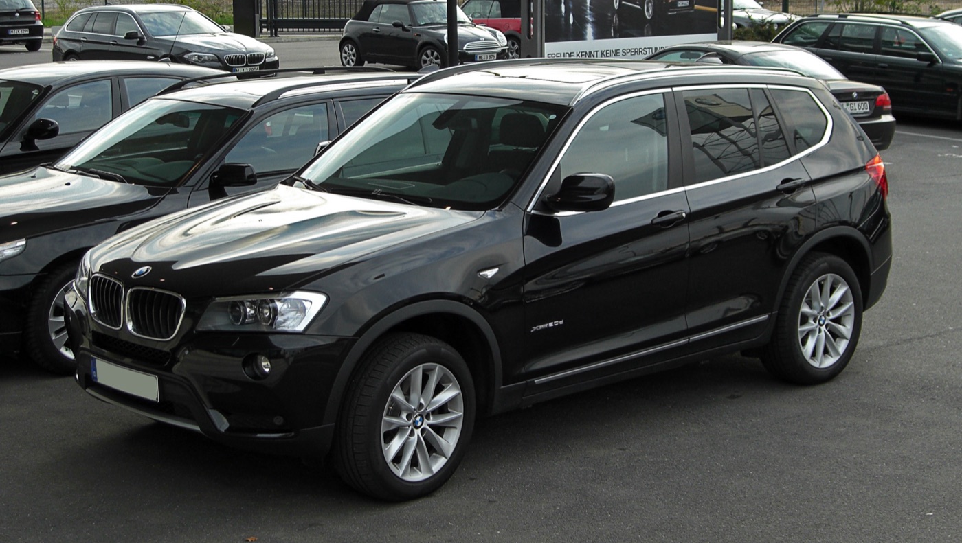 Black pre-facelift BMW X3 xDrive20d F25 parked at a BMW dealer, seen from the front three-quarter