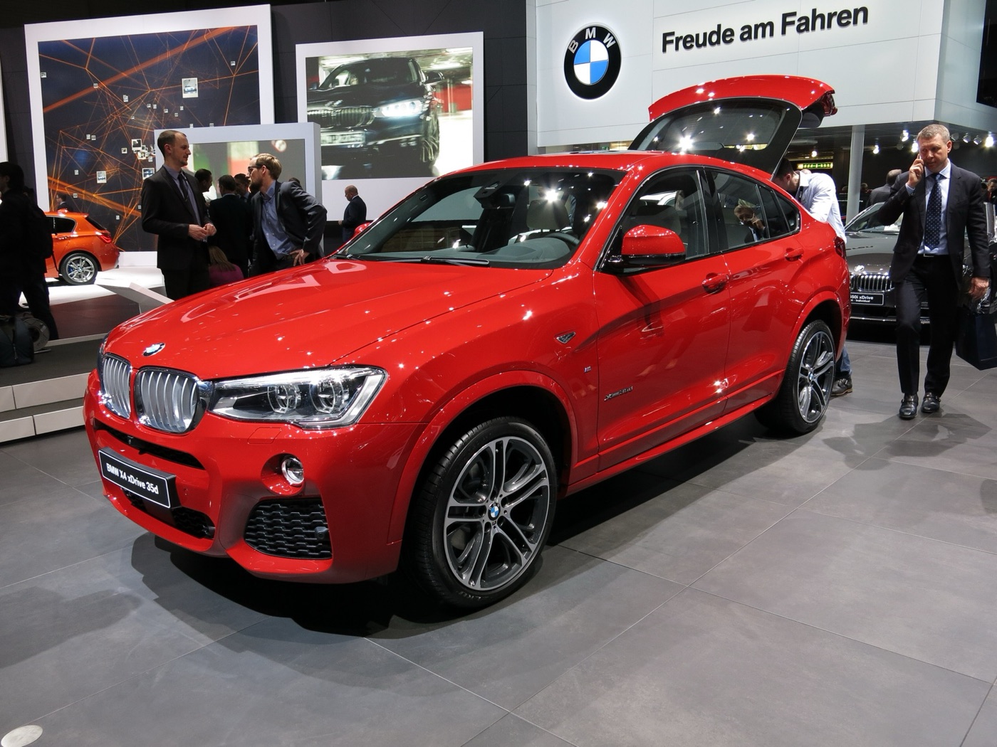 Red BMW X4 F26 with its tailgate open on the BMW stand at a motor show