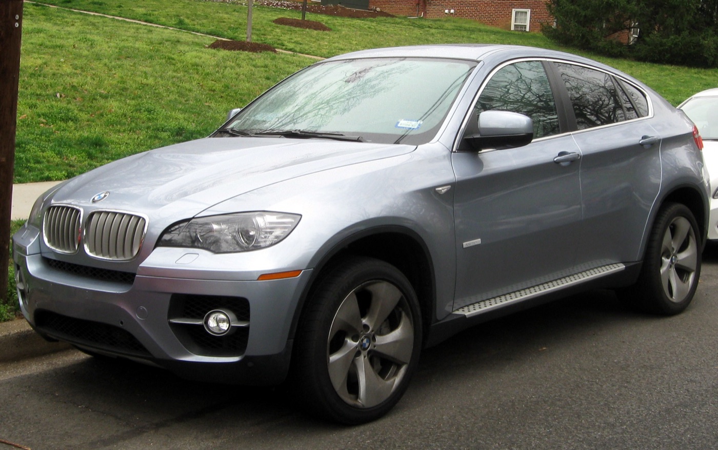 Pale blue-grey BMW ActiveHybrid X6 parked on a street with grass behind