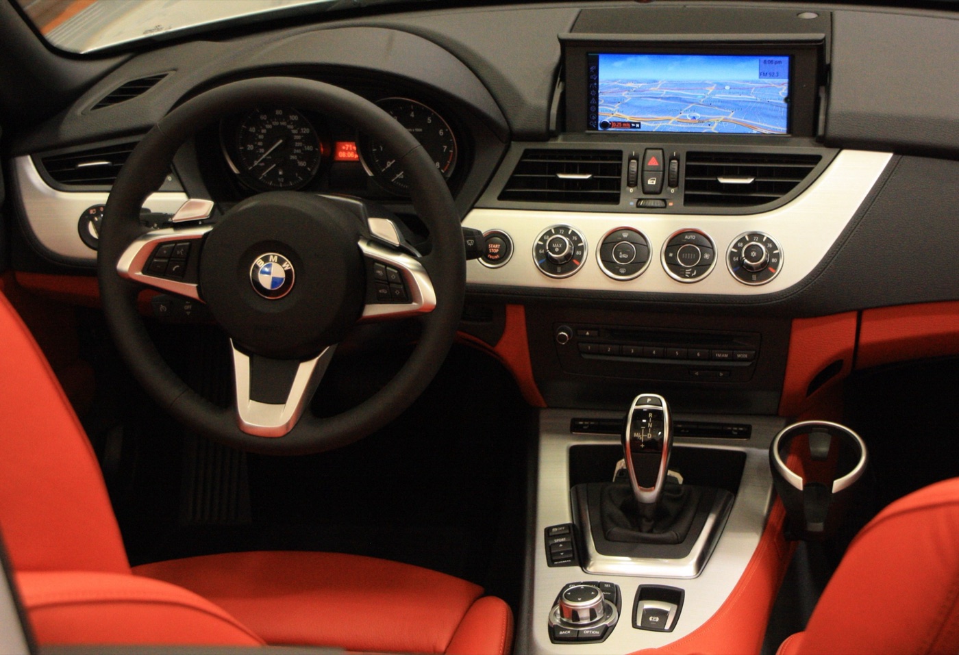 Dashboard of a BMW Z4 E89 with red leather seats, the iDrive screen raised and the dual-clutch gear selector