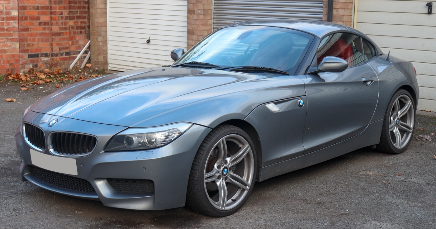 Grey BMW Z4 E89 sDrive23i M Sport with its folding hard top closed, parked in front of garages