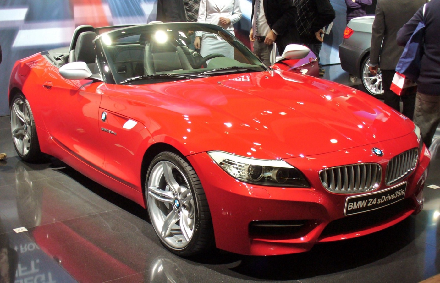 Red BMW Z4 sDrive35is with the roof folded and five-spoke wheels, on a motor show stand