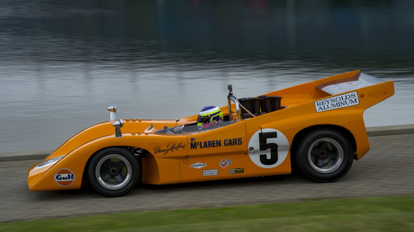 Orange McLaren M8D Can-Am car with Denny Hulme’s name and number 5 being driven beside a lake