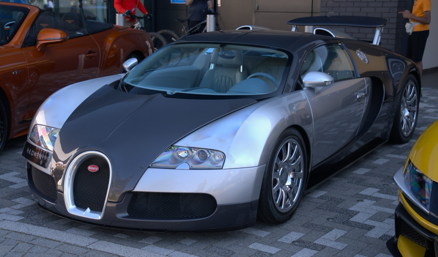 Silver and dark grey two-tone Bugatti Veyron 16.4 coupé parked on block paving, seen from the front three-quarter