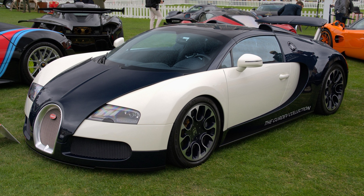 Cream and dark blue Bugatti Veyron Grand Sport on grass at a car show, with dark multi-spoke wheels